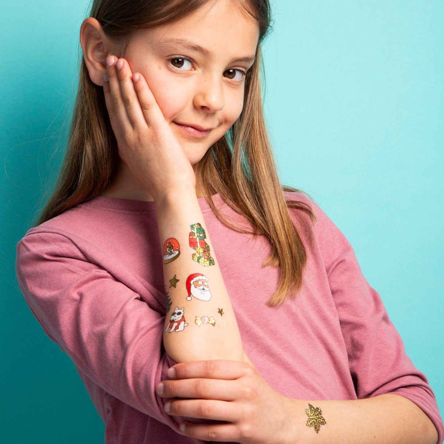 Girl with temporary tattoos on her arm against a teal background