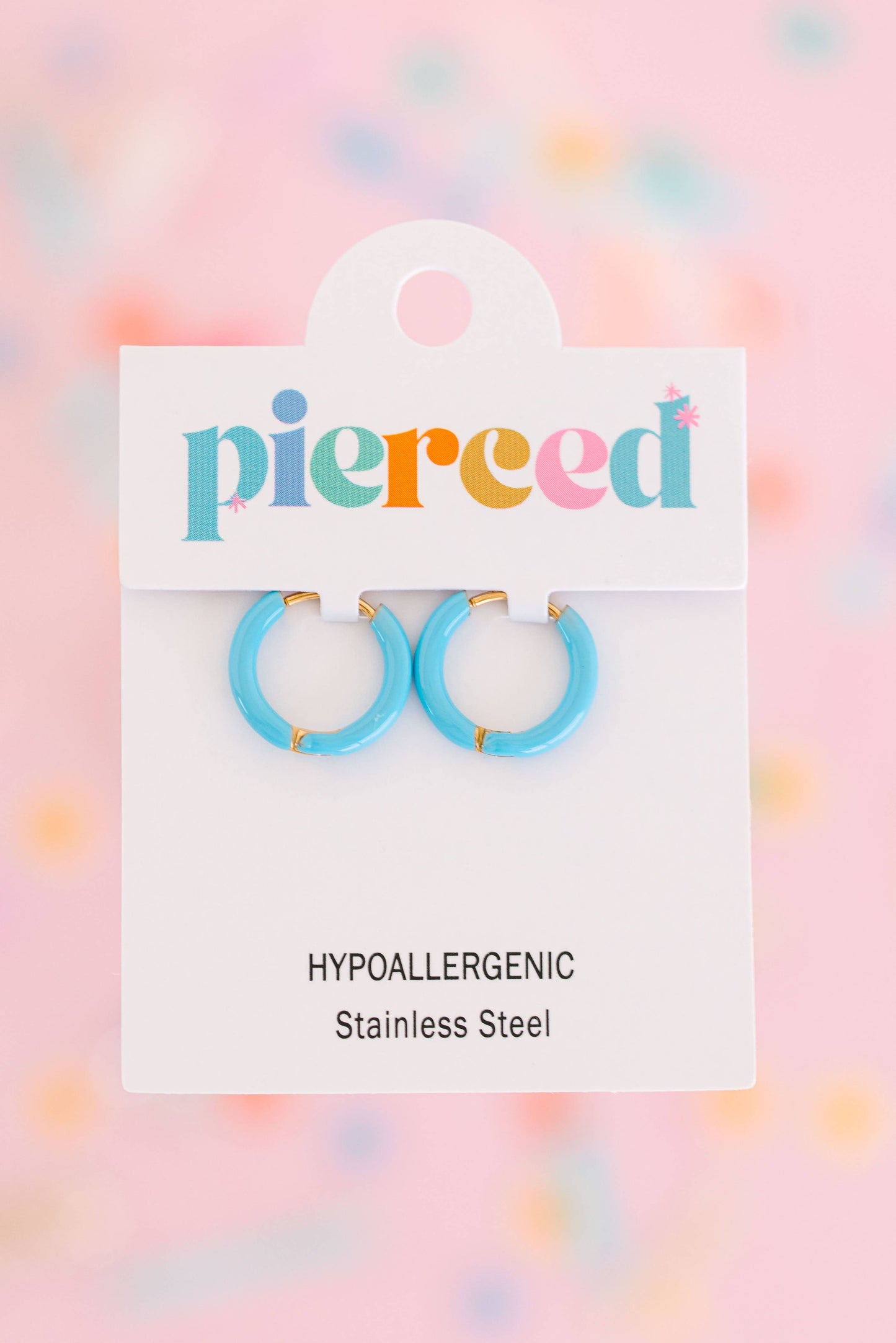 Pair of blue hoop earrings on a 'pierceed' branded card with a colorful blurred background.
