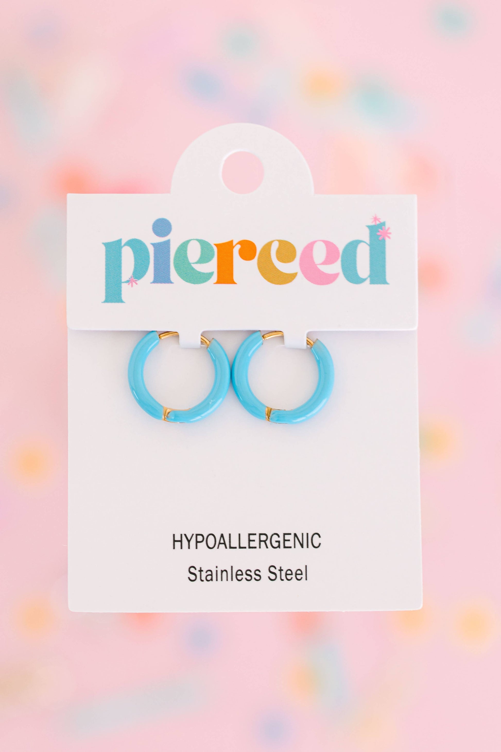 Pair of blue hoop earrings on a 'pierceed' branded card with a colorful blurred background.