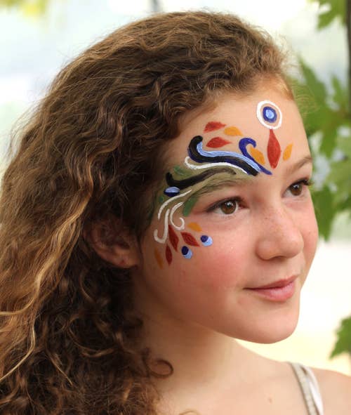 Girl with colorful face paint against a natural background