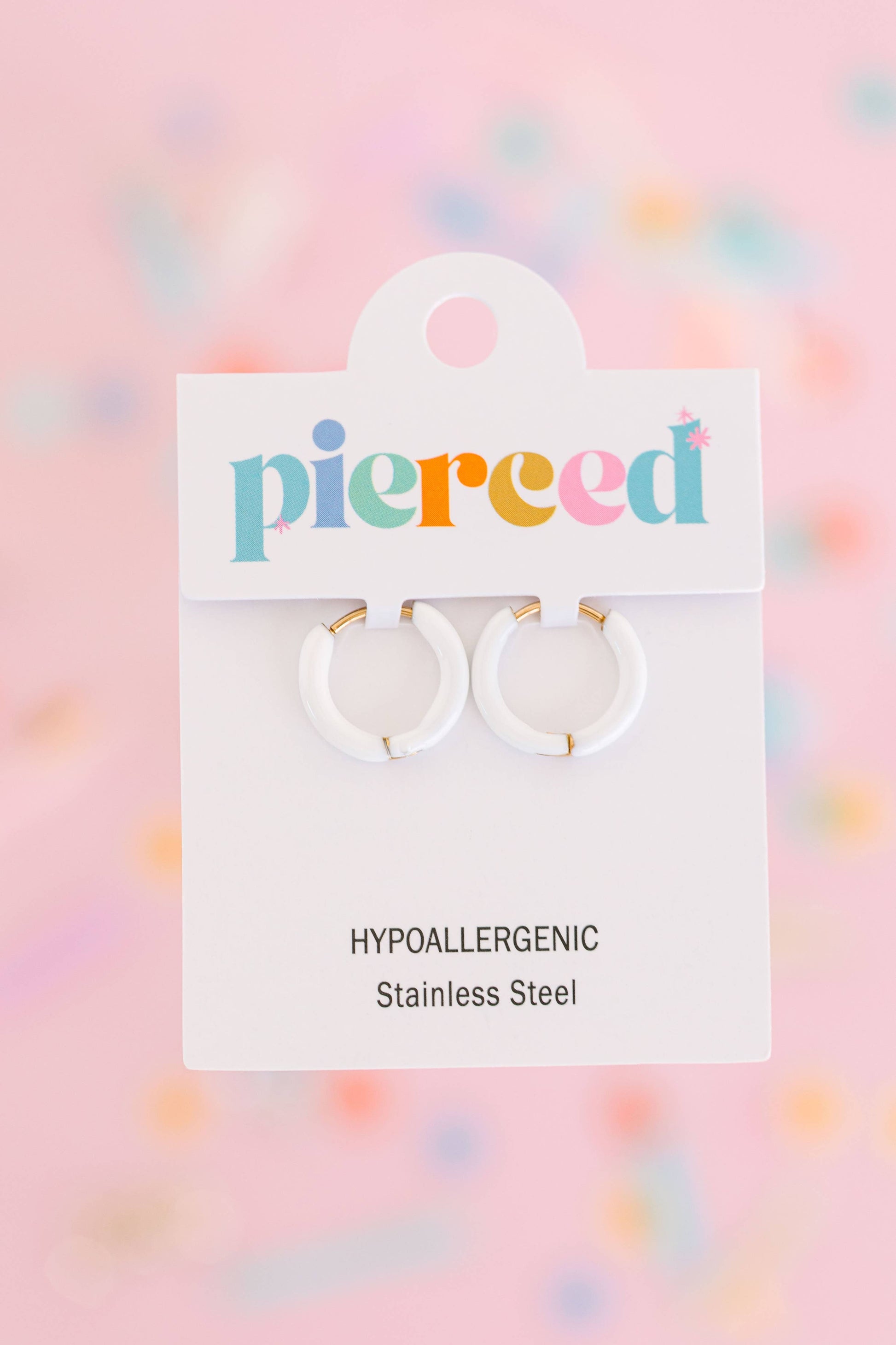 Pair of hoop earrings on a 'pierced' branded card with a colorful blurred background