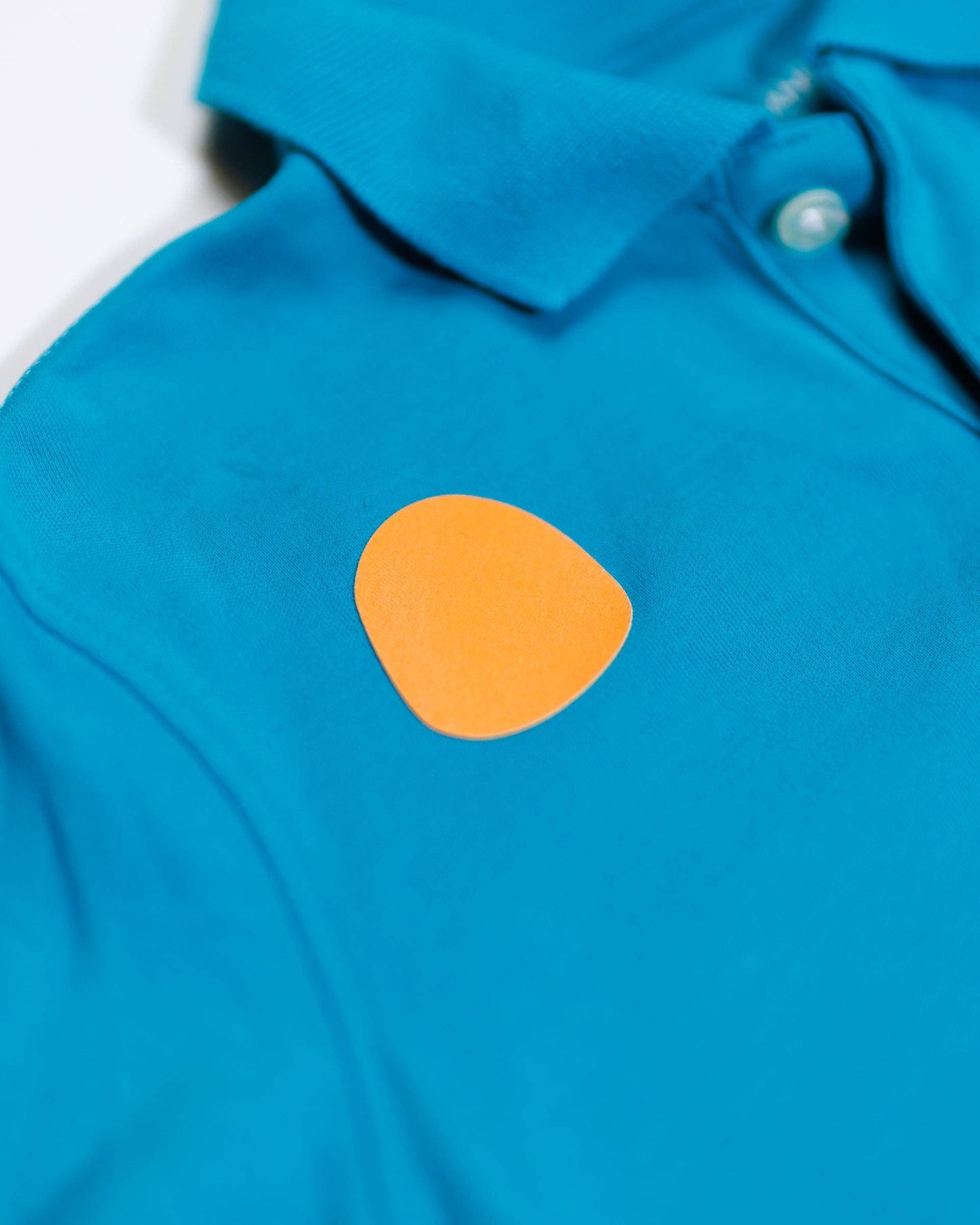 Blue shirt with an orange circle patch on a white background