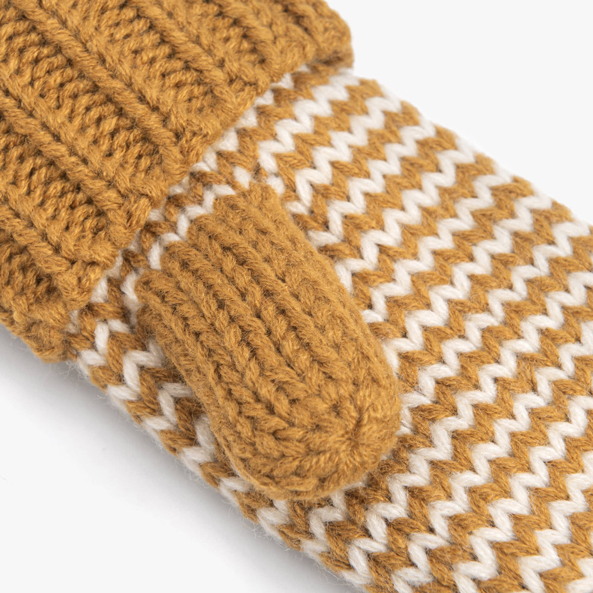 Close-up of a chunky knit mittens in a warm camel brown with a white chevron pattern.