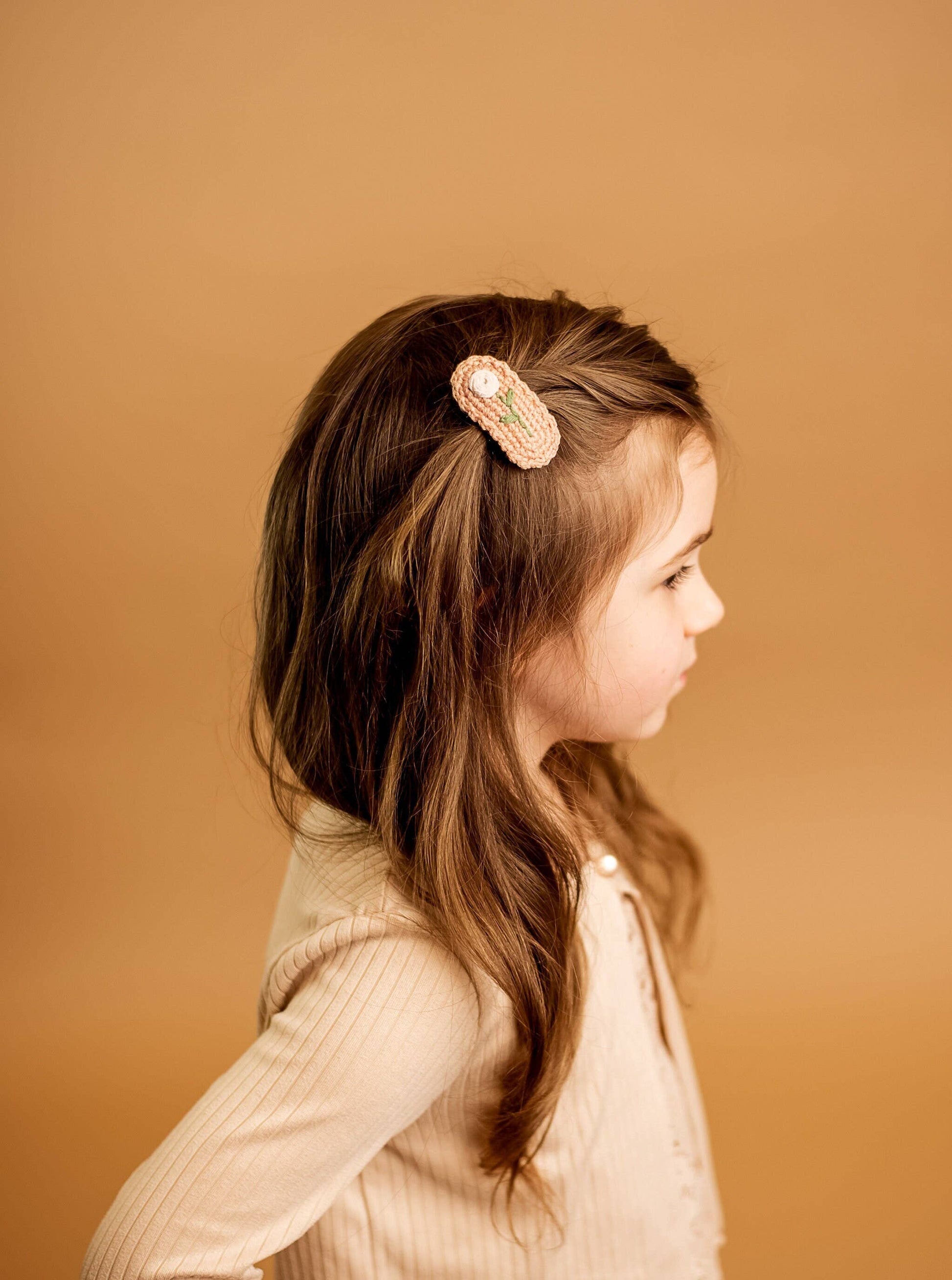 Young girl with a decorative hair clip on a beige background