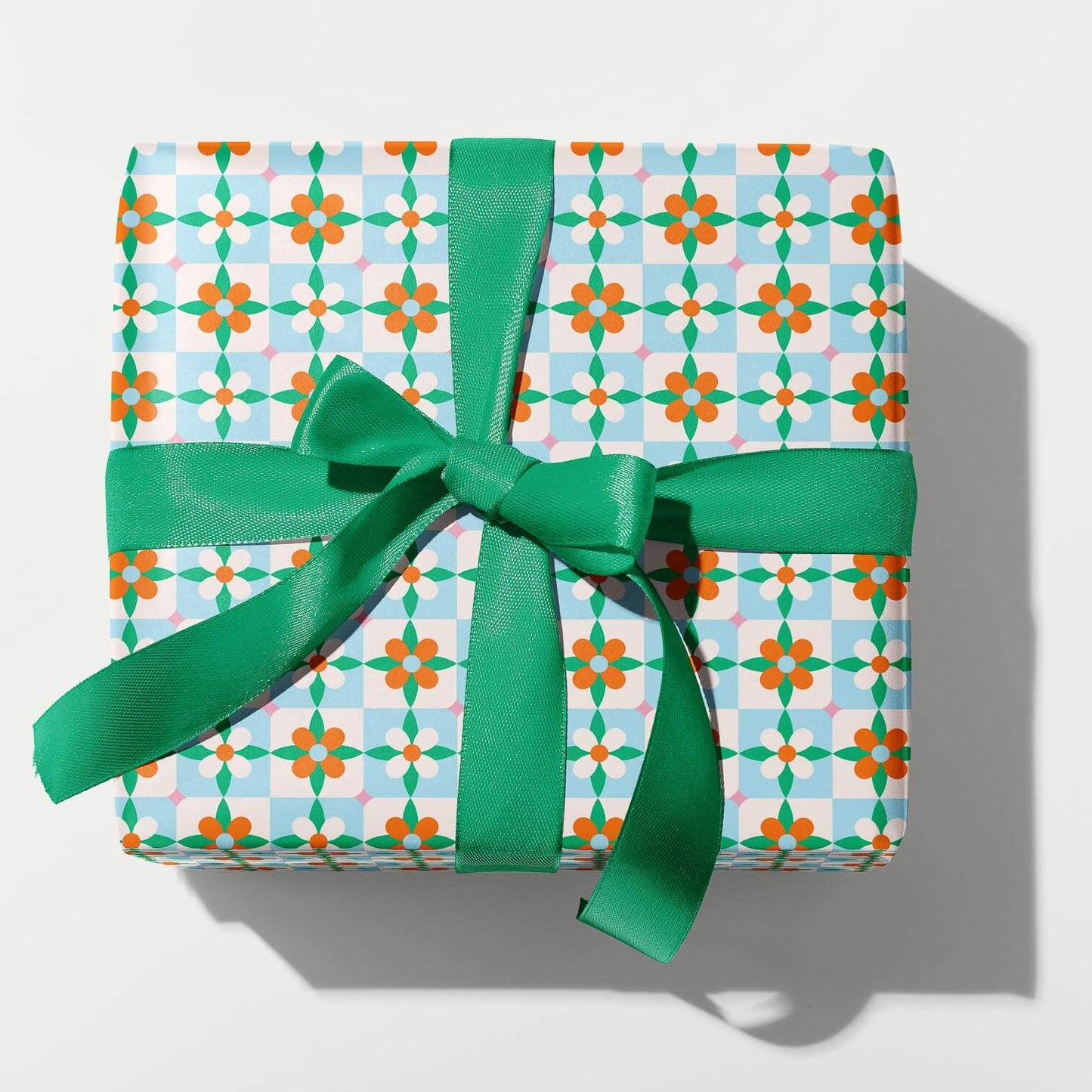 Gift box with patterned paper and green ribbon on a white background