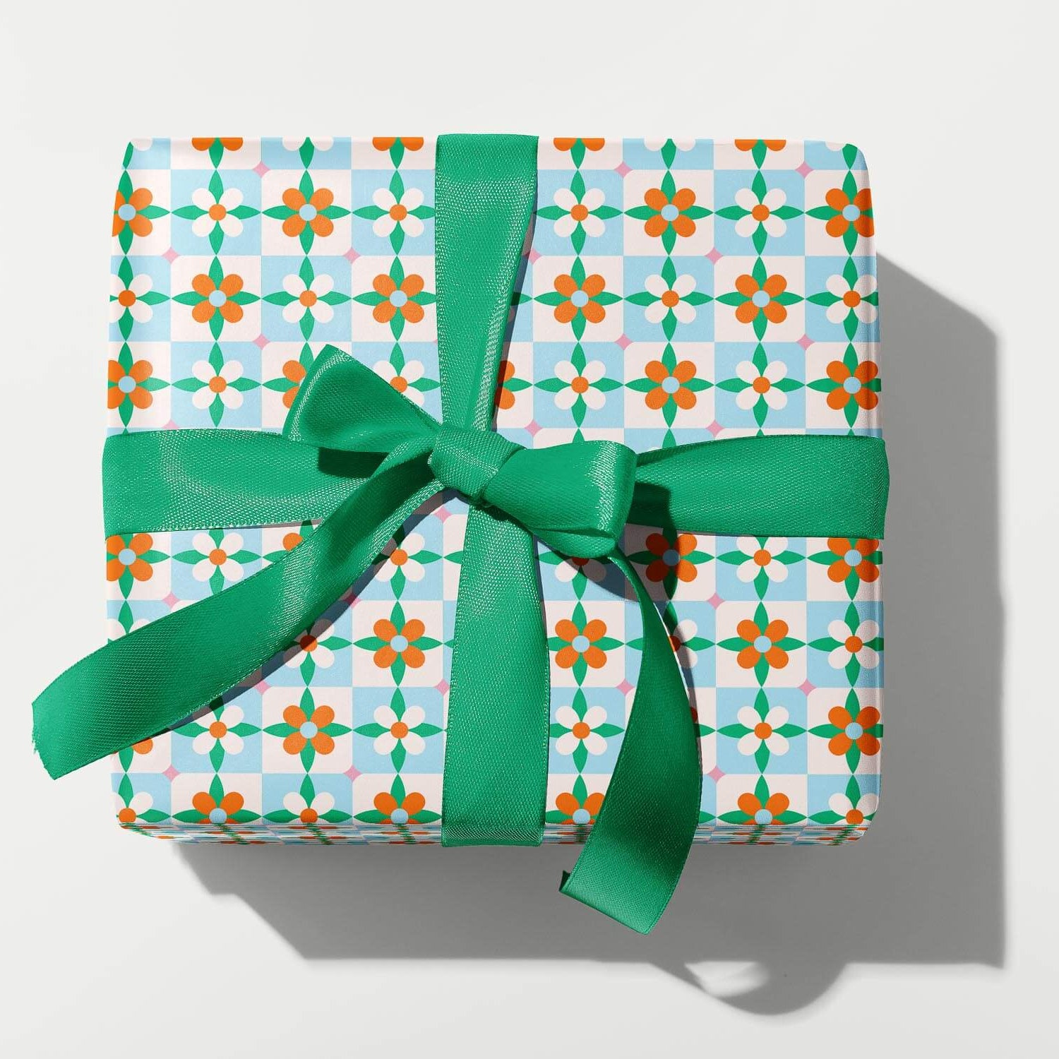 Gift box with patterned paper and green ribbon on a white background