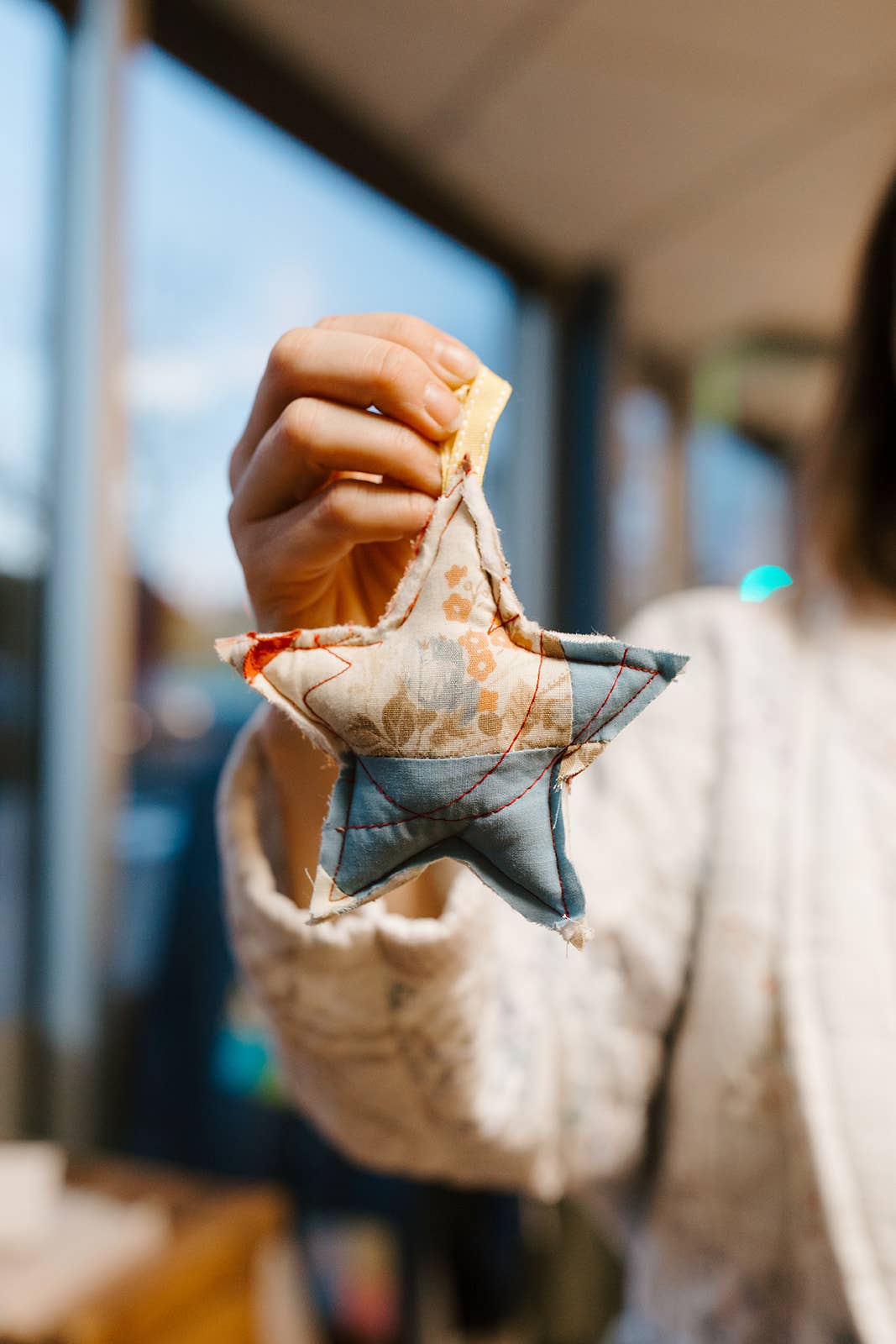 Person holding a small star-shaped fabric item with a blurred background