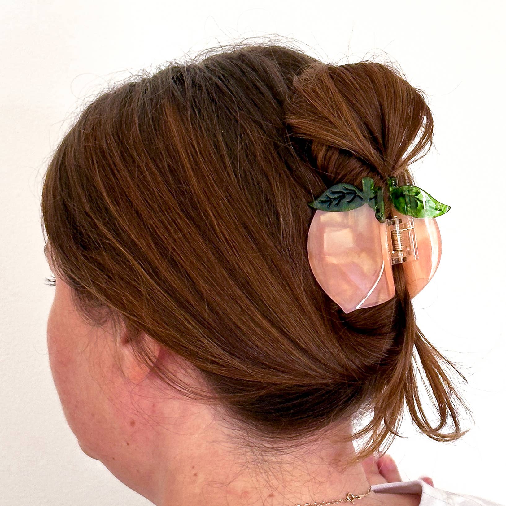 Person with hair styled using a decorative hair clip on a plain background
