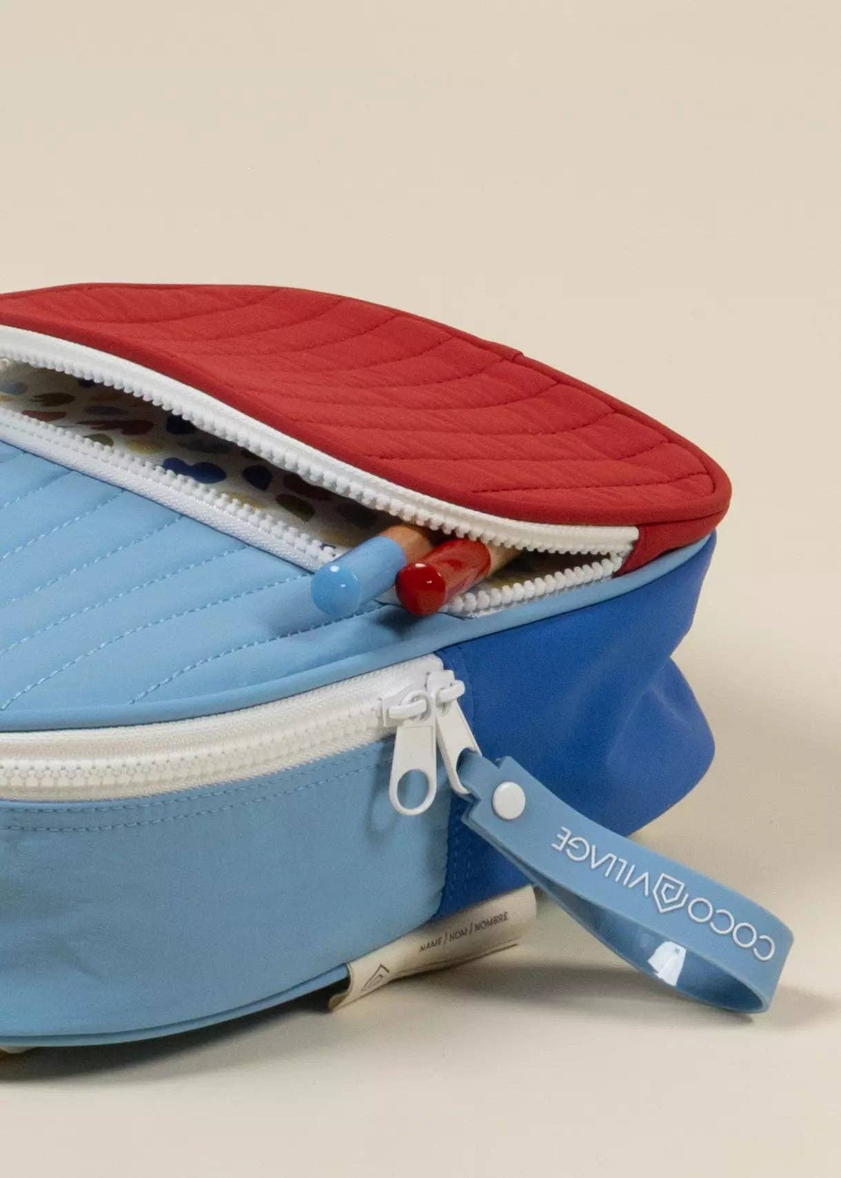 Blue and red backpack with a visible brand label on a beige background