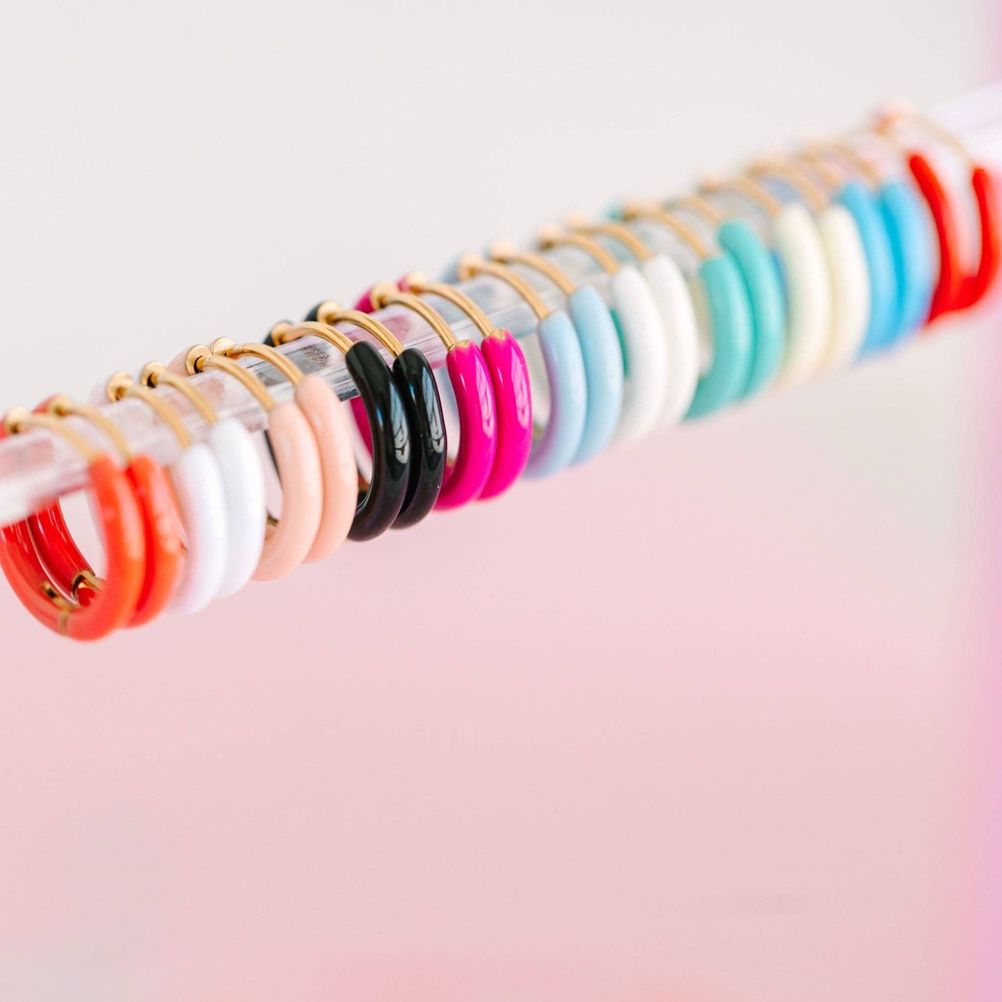 Row of colorful earrings on a pink background