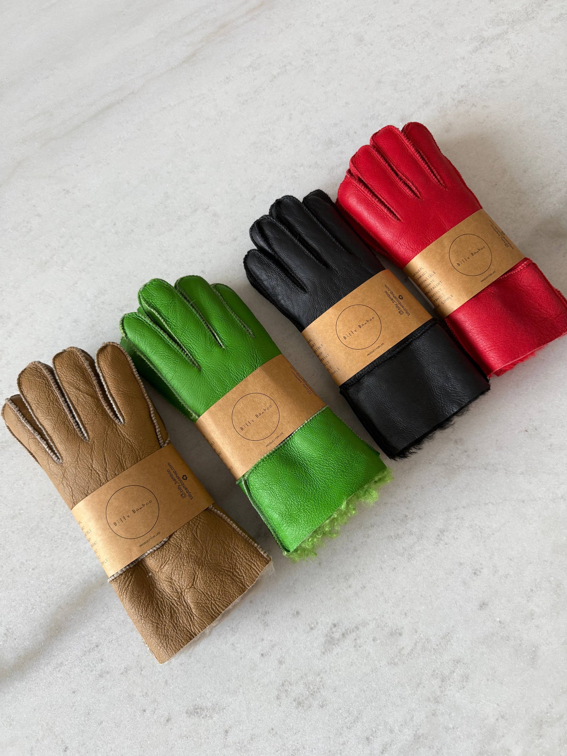 leather gloves in brown, green, black, and red on a light gray surface.