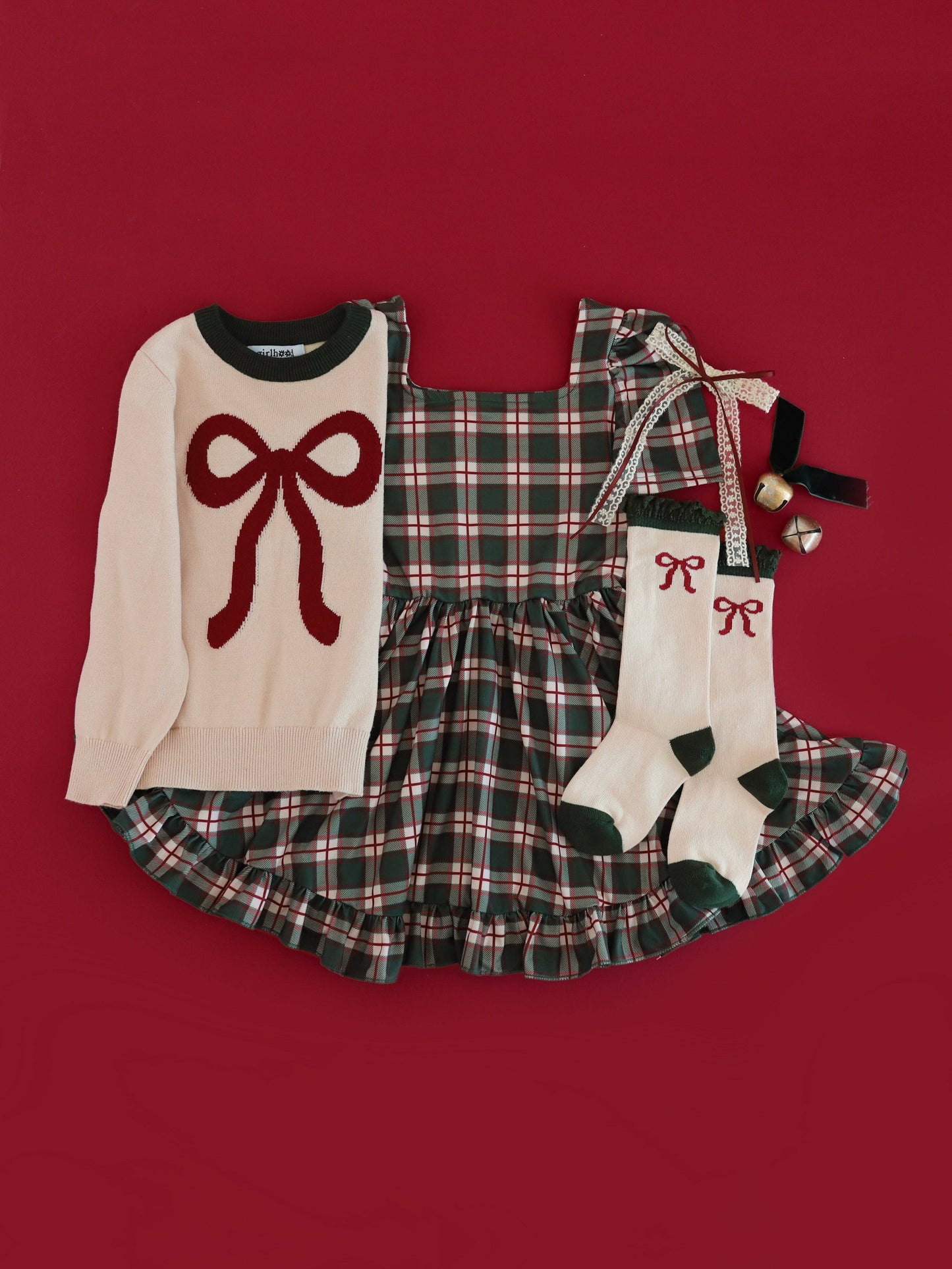 Children's outfit with sweater, dress, and socks on a red background