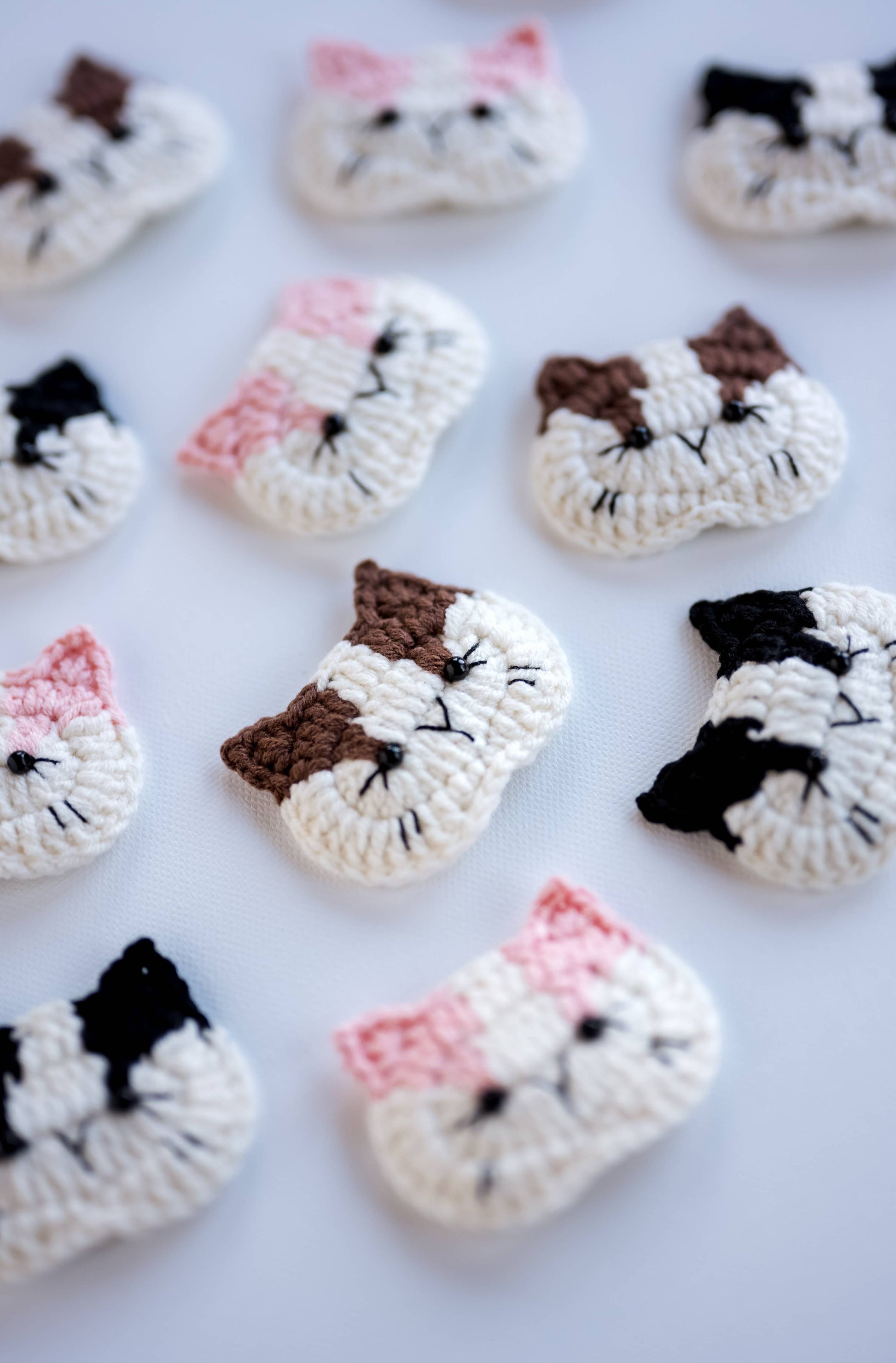 Crocheted cat face patterns on a white background