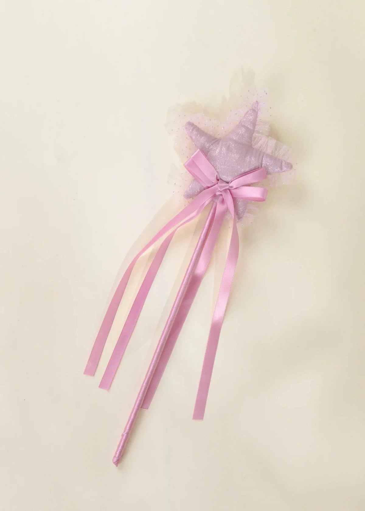 A pink and lavender star-shaped wand with a lace-topped star, pink satin ribbon bow, and long pink ribbon tails, shown on a plain cream background.