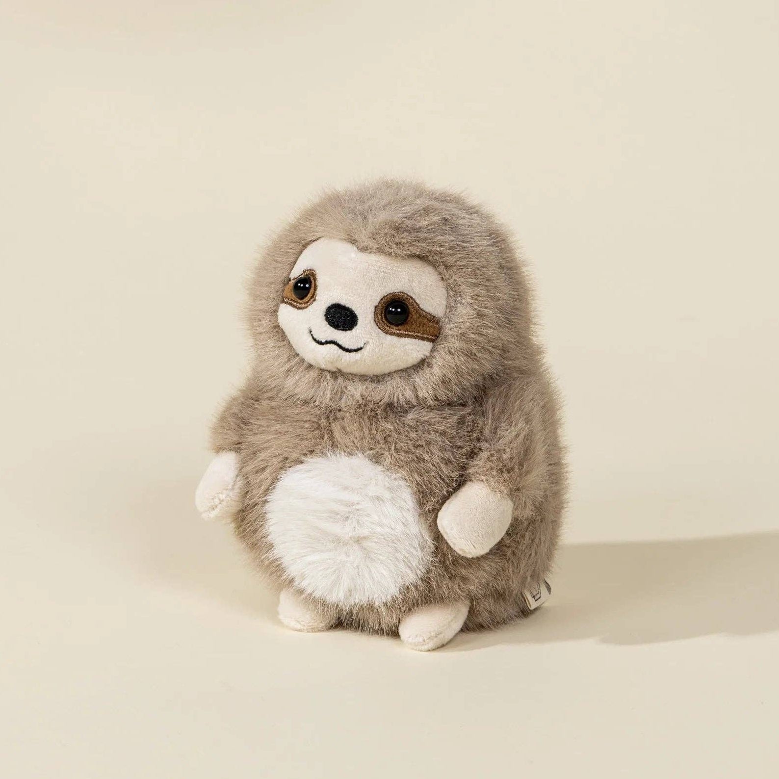 Plush toy sloth on a beige background