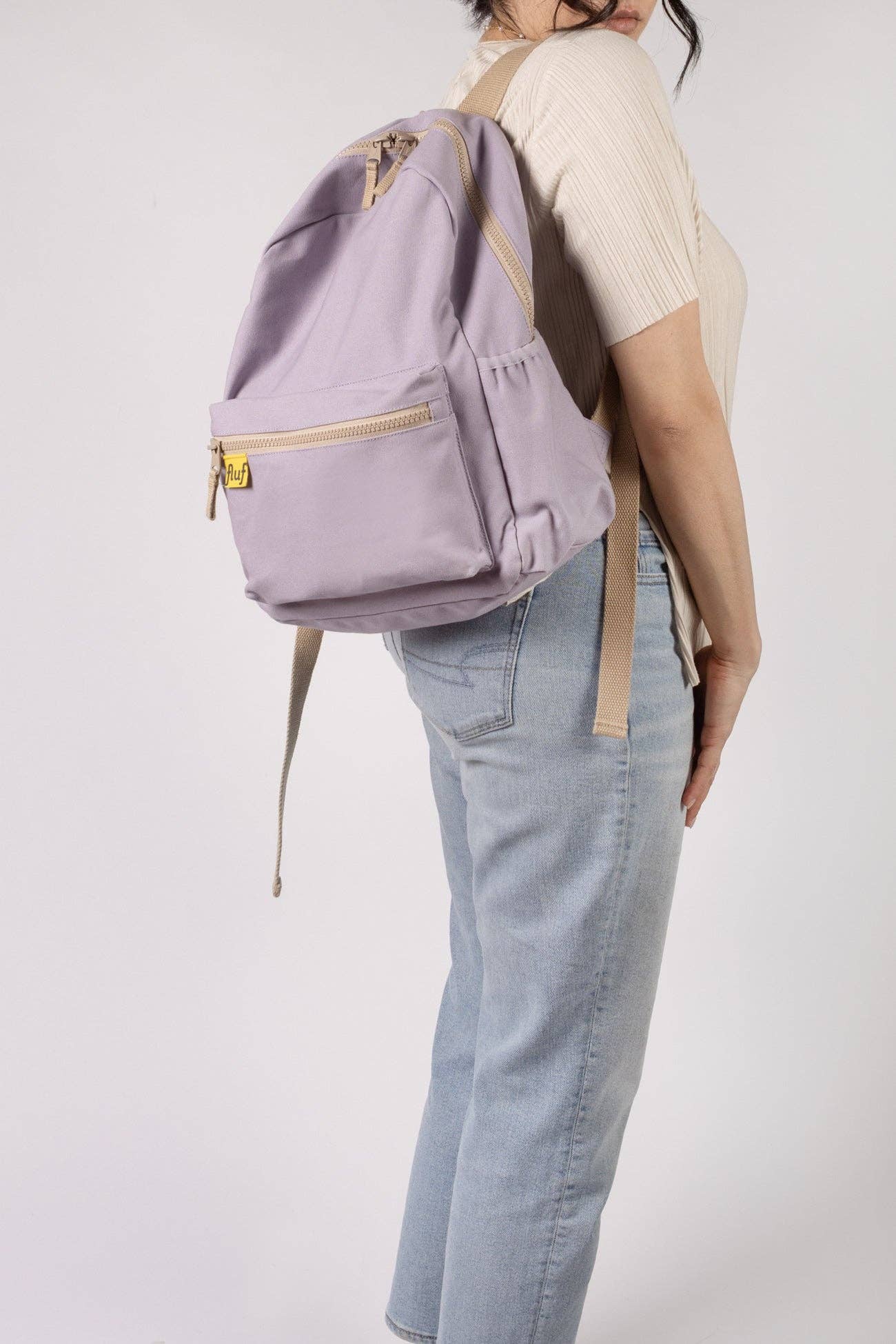 Person wearing a lavender backpack with gold accents on a plain background