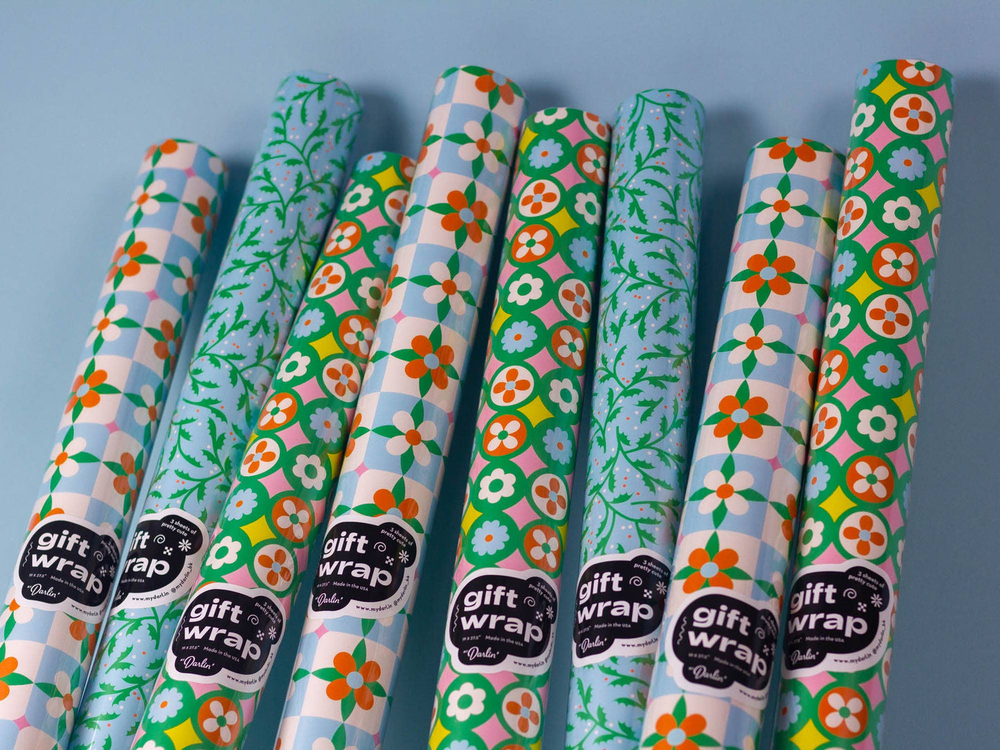 Set of colorful gift wrap rolls with floral patterns on a blue background
