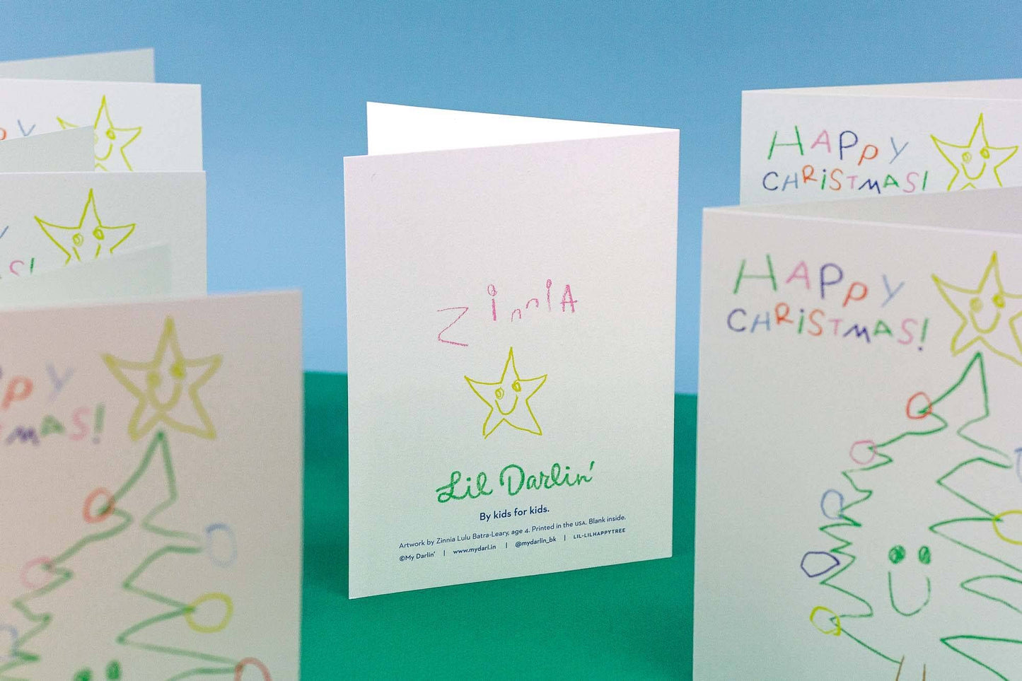 Collection of hand-drawn Christmas cards with stars and trees on a blue and green gradient background.