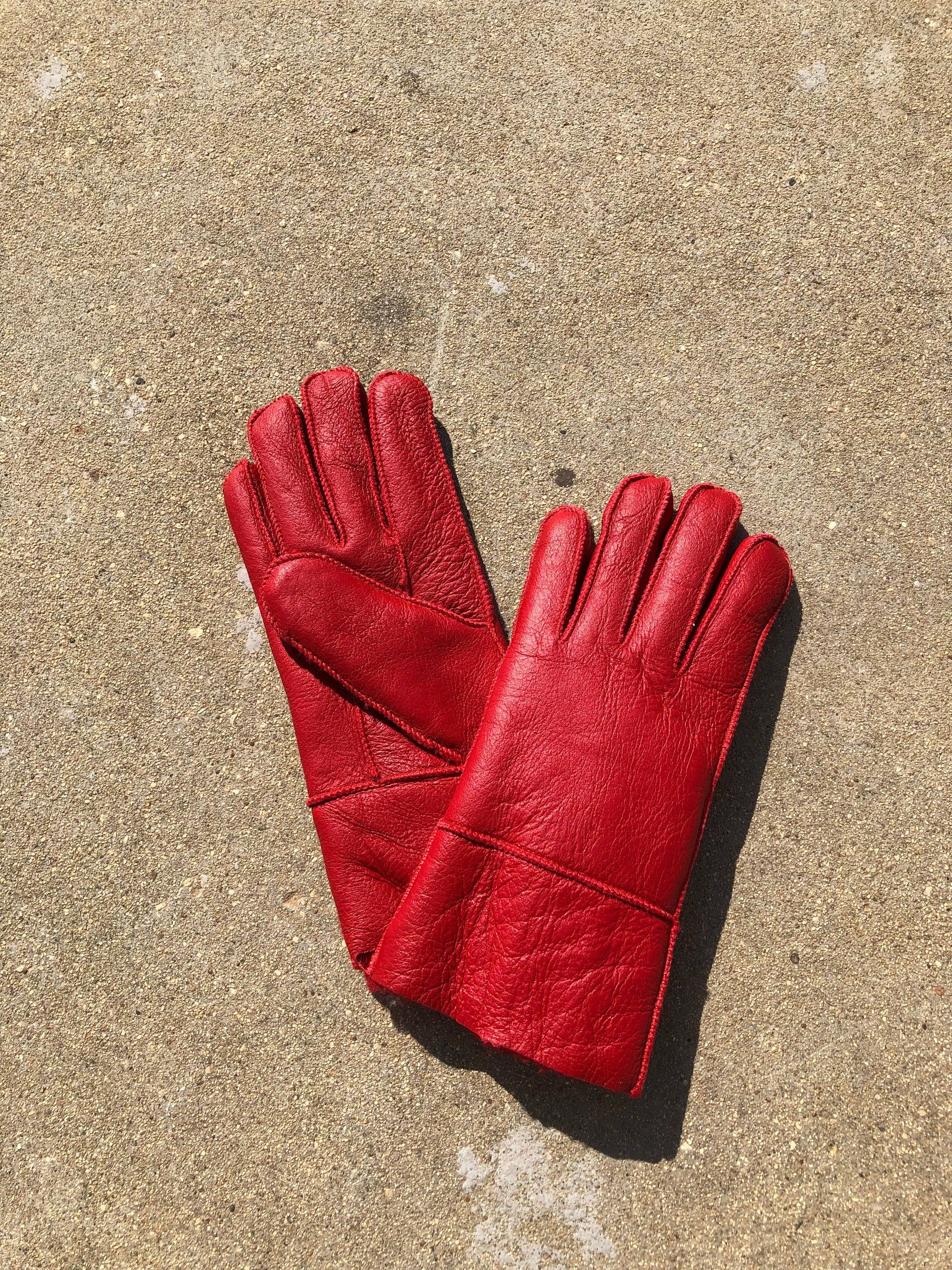 Pair of red leather gloves on a concrete surface