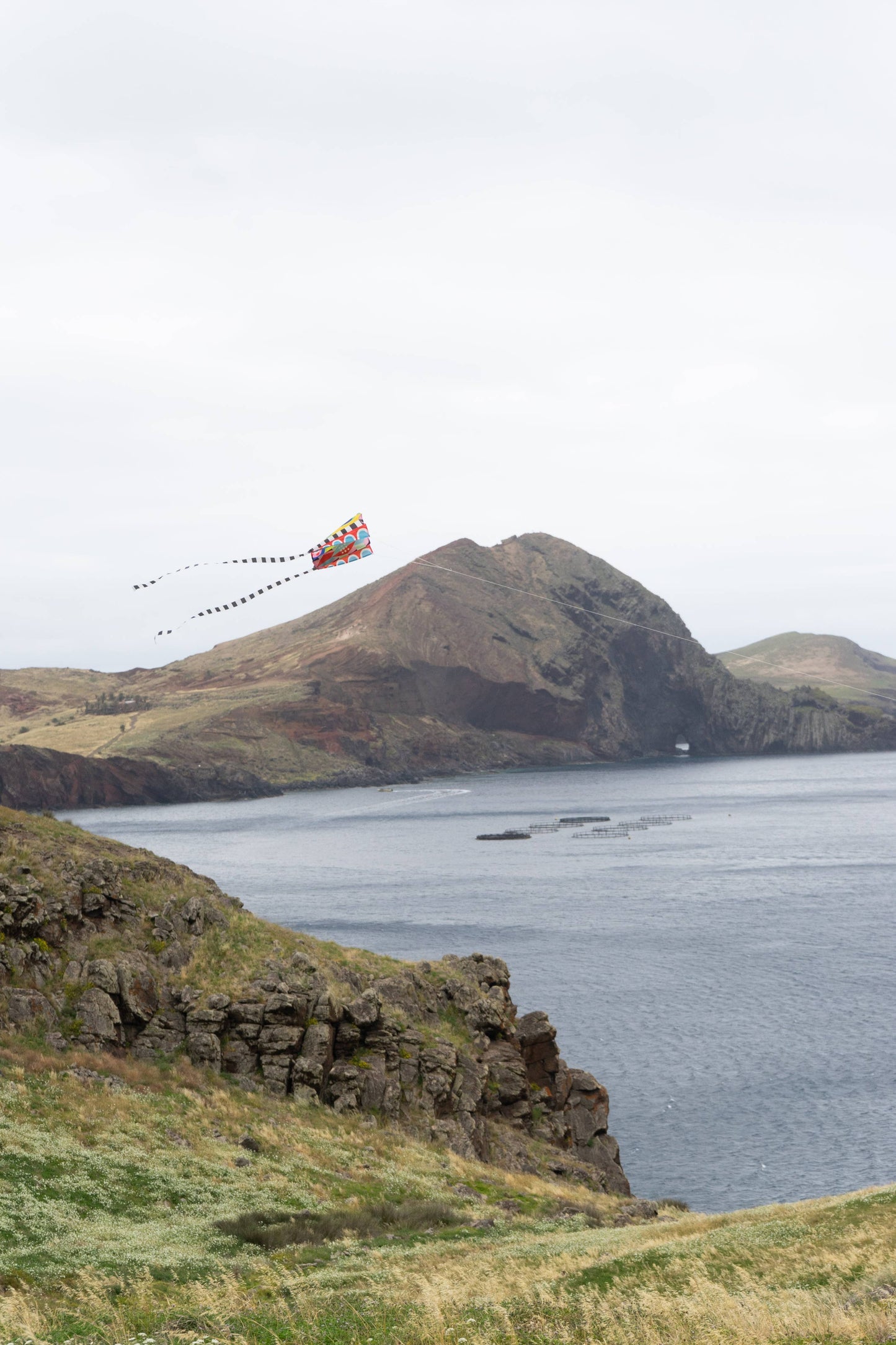 Kite flying over a mountainous landscape with a body of water.