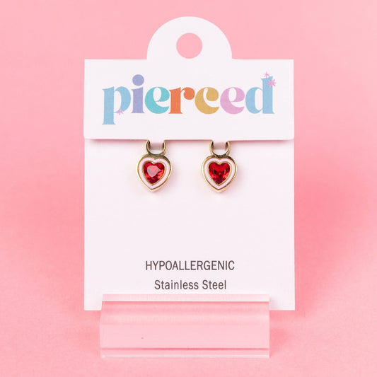 Heart-shaped earrings on a 'pierced' branded card against a pink background