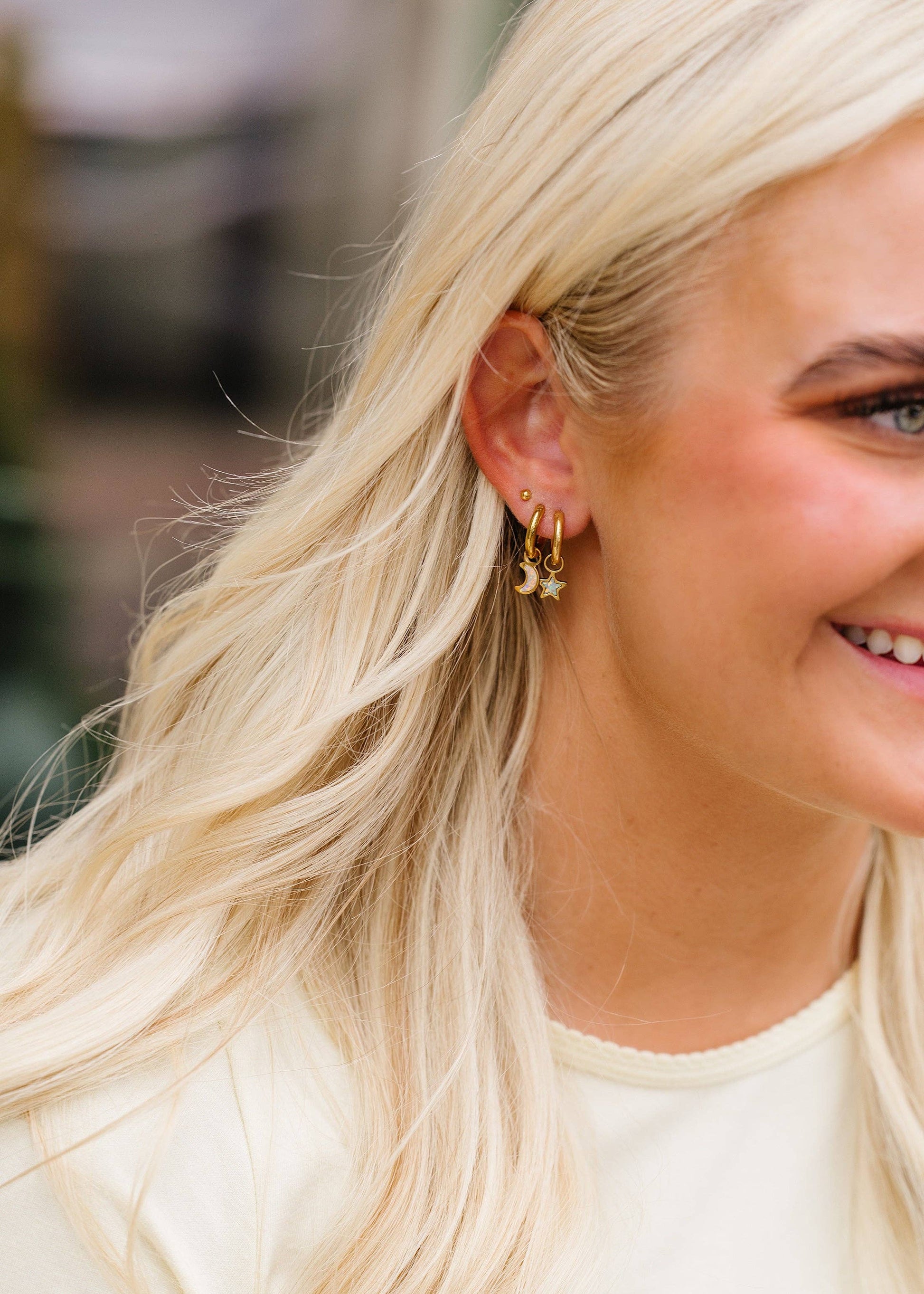 Close-up of a woman wearing gold earrings with a blurred background