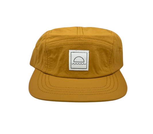 Mustard yellow cap with a logo patch on a white background