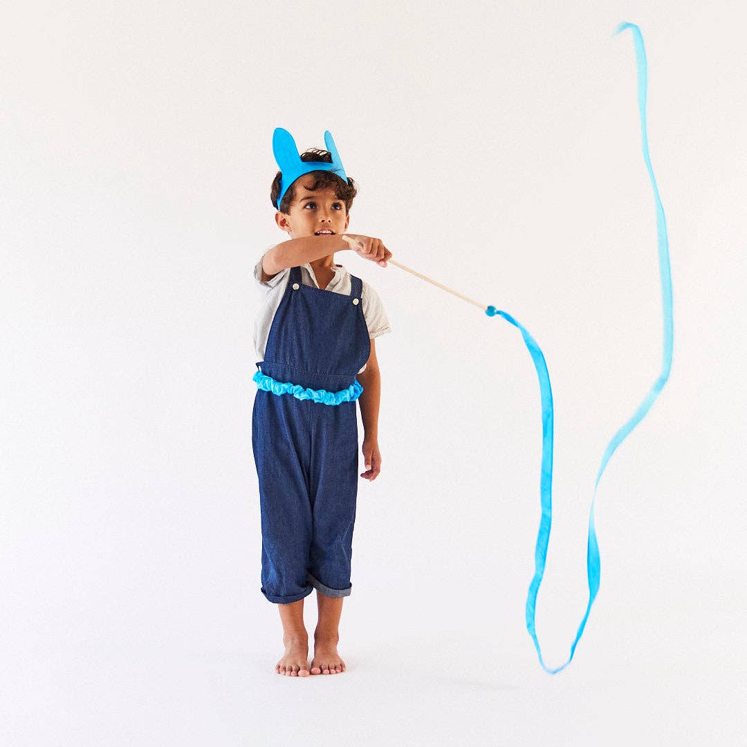 Child wearing a blue outfit with a cat-like design, holding a blue ribbon.
