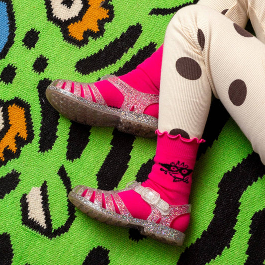 Child's feet wearing pink socks on a colorful rug