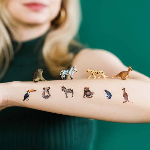 Miniature animal tattoos on a person's arm with a green background