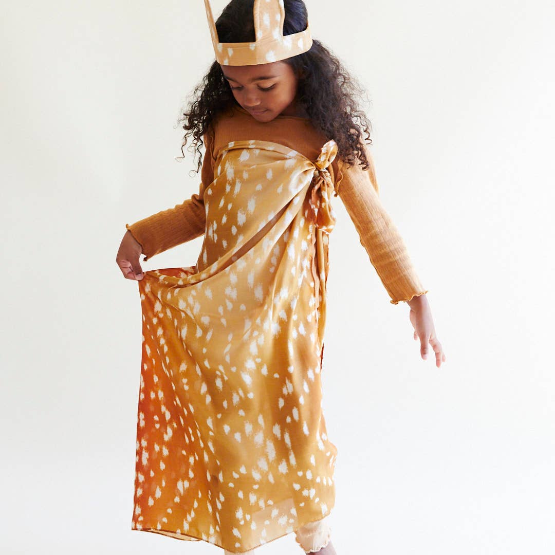 Child wearing a deer-themed dress and crown on a white background