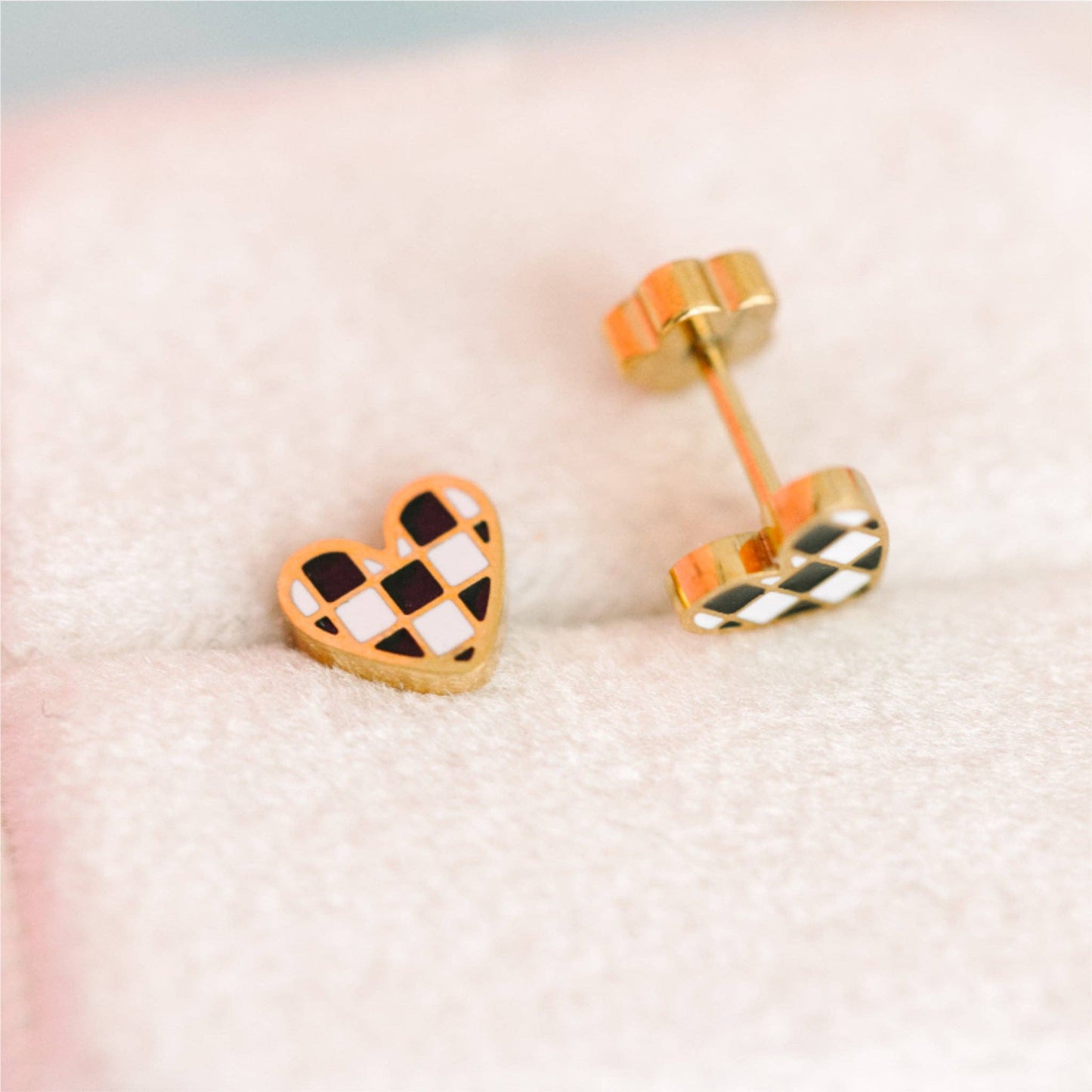 Heart-shaped checkered earrings on a soft pink background