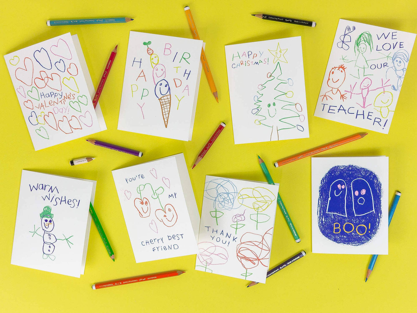 Colorful children's drawings on paper with pencils on a yellow background