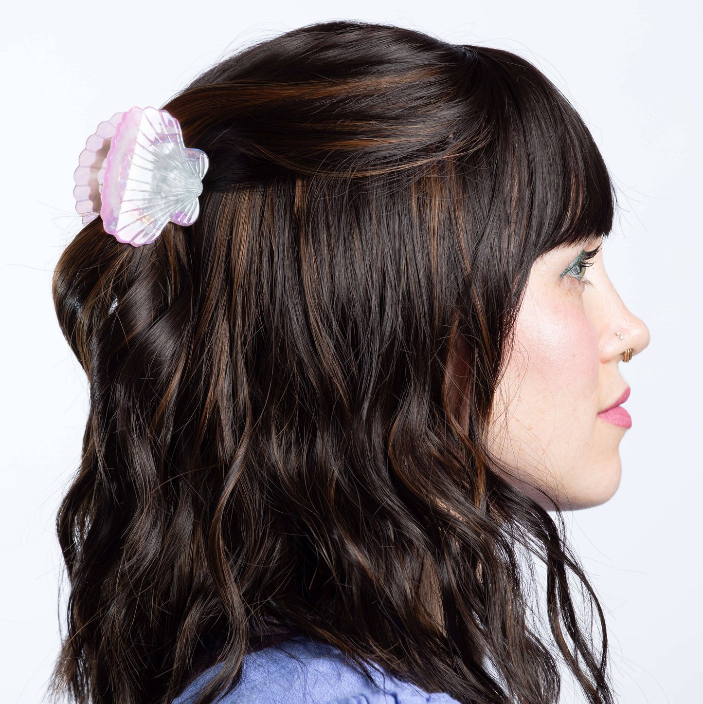 Woman with wavy hair featuring a decorative hair clip on a white background