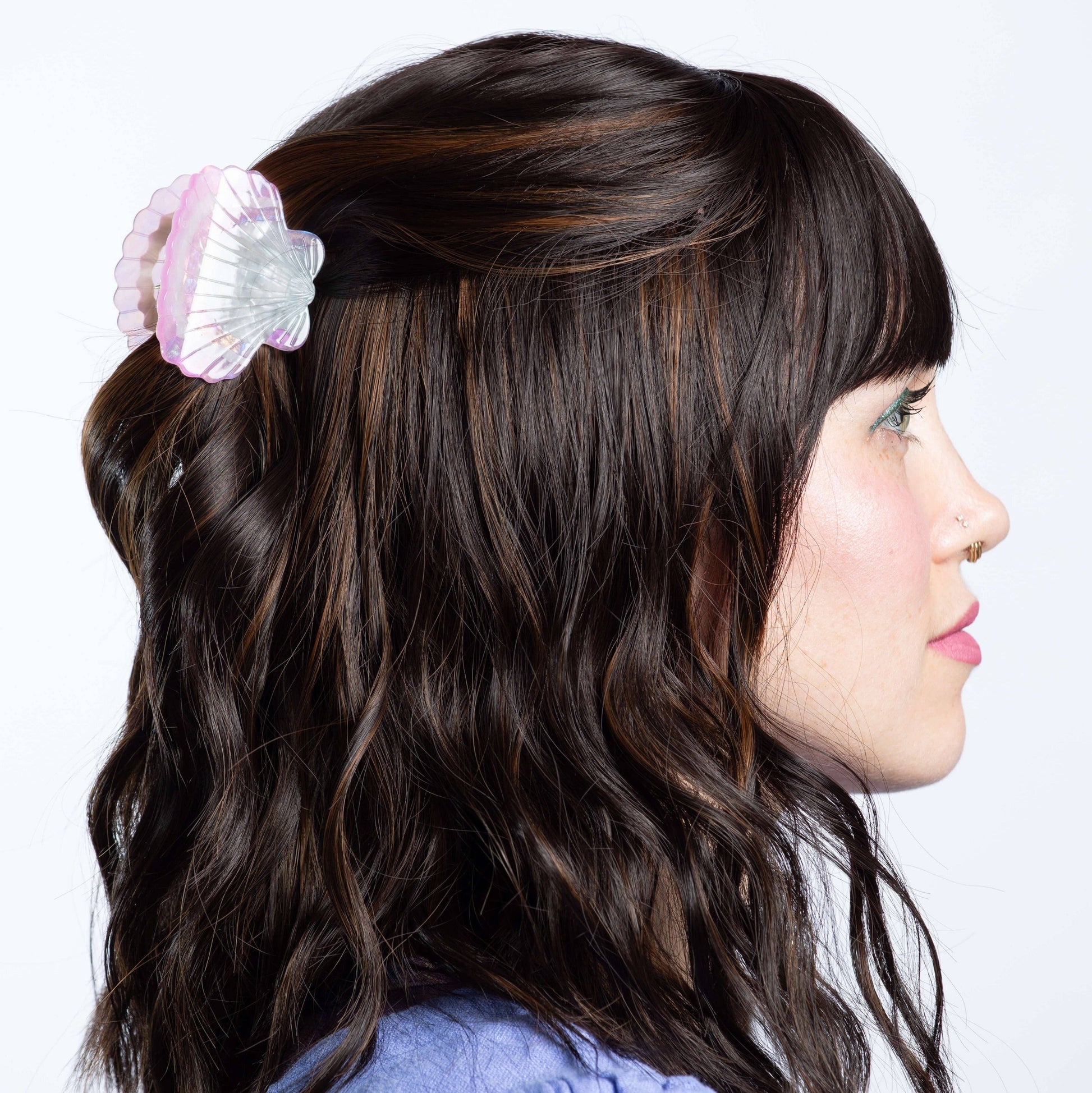 Woman with wavy hair featuring a decorative hair clip on a white background