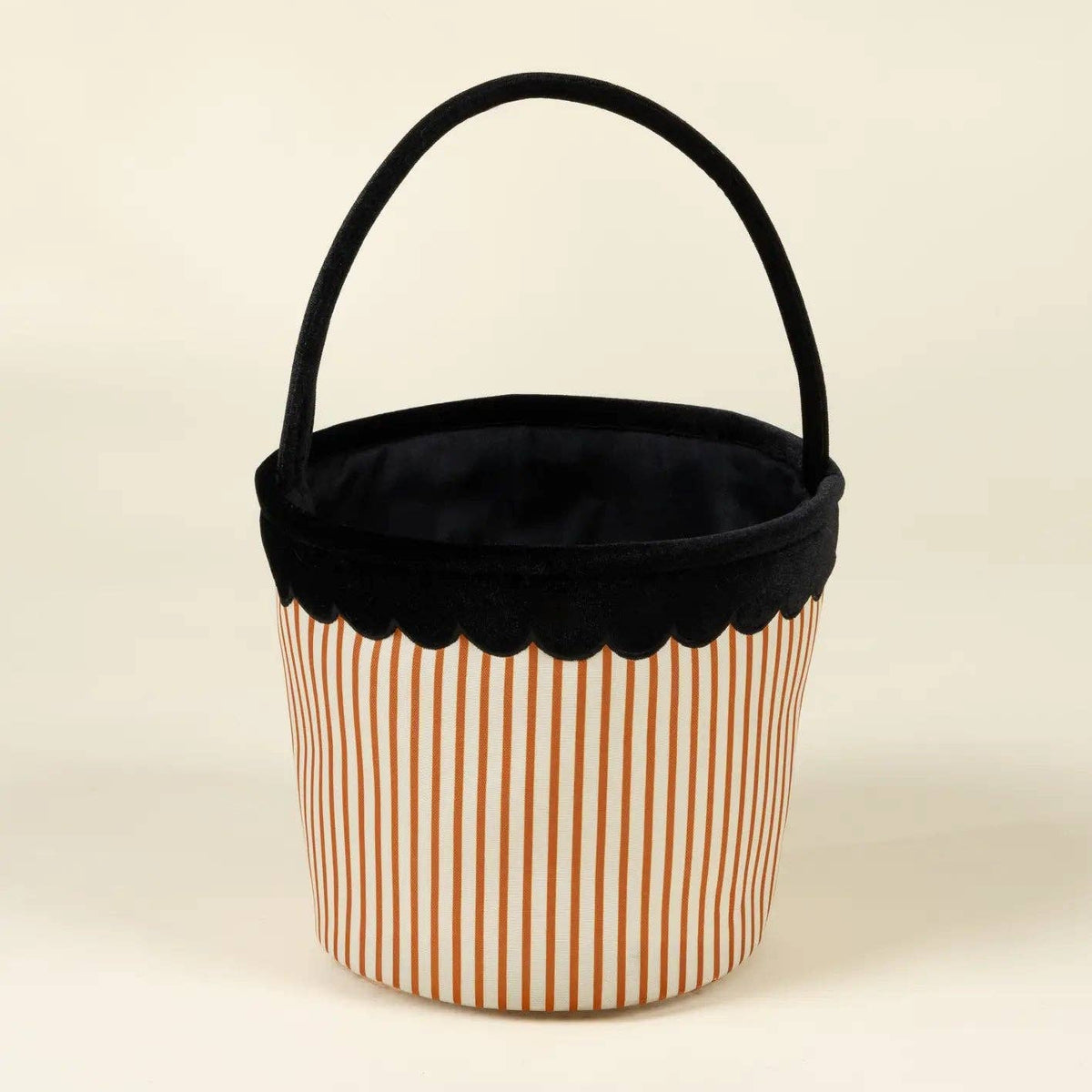 A small fabric storage basket with a black velvet handle and trim, featuring a white body with thin orange vertical stripes, set against a plain cream background.