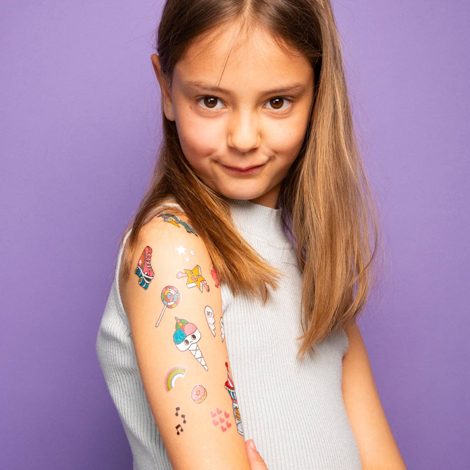 Young girl with temporary tattoos on her arm against a purple background
