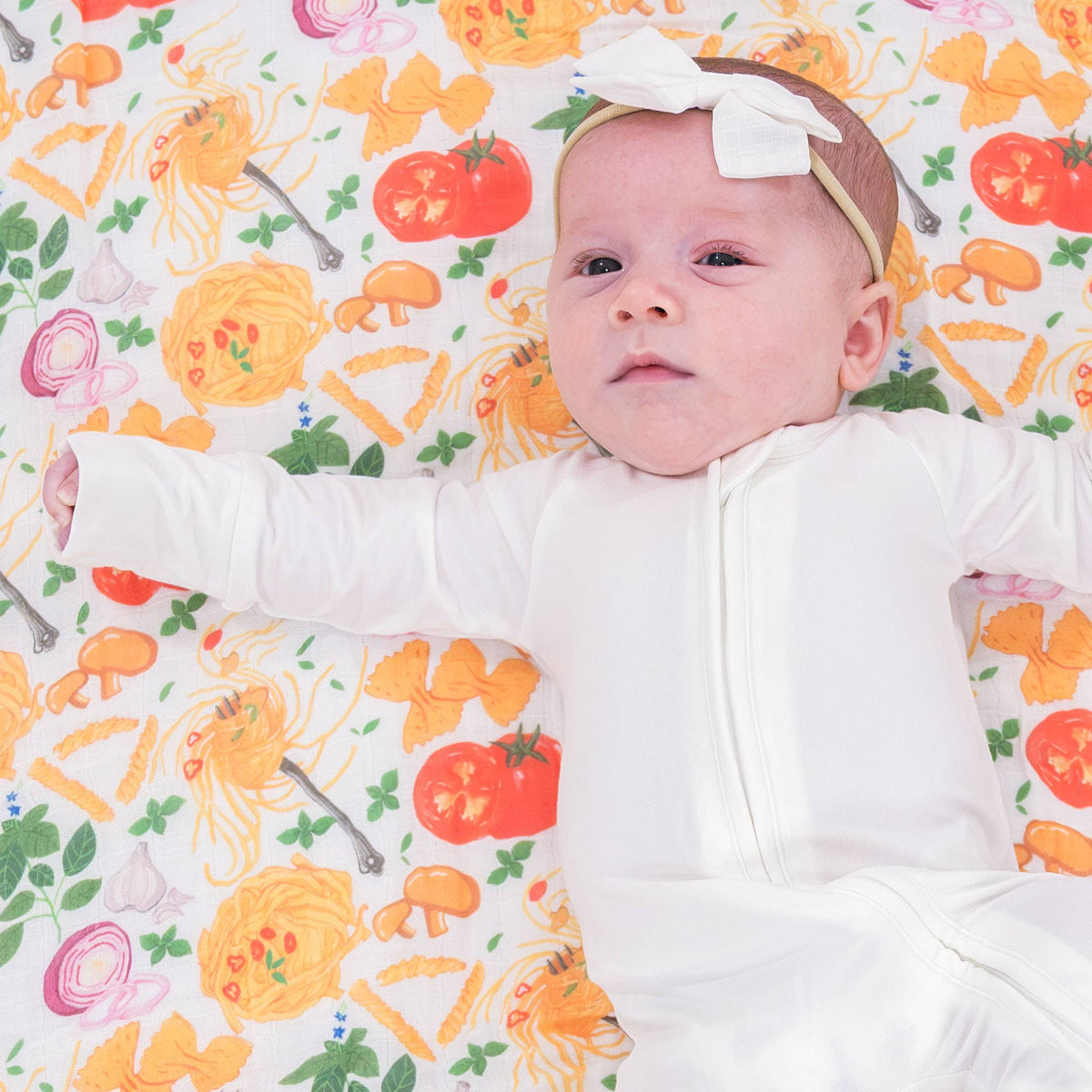 Baby lying on a colorful blanket with cartoon food patterns