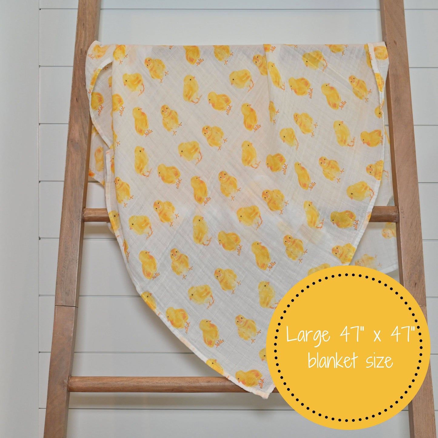 Baby blanket with yellow duck pattern draped over a wooden ladder on a white background