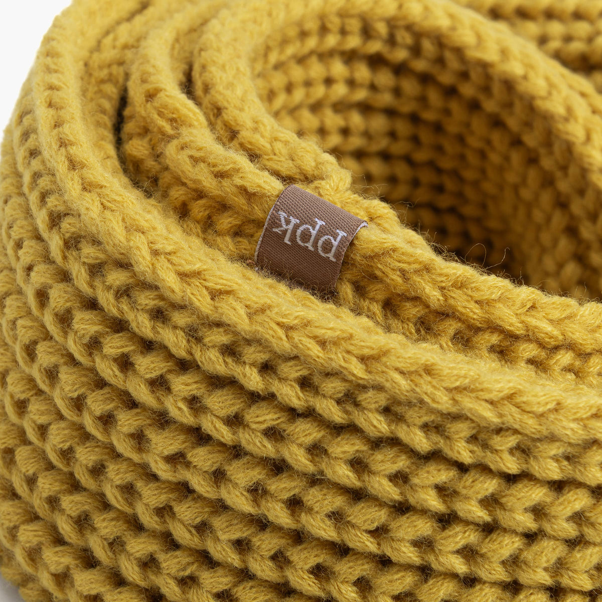 Close-up of a yellow knitted product with a brand label on a white background