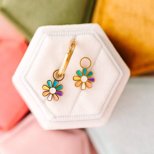 Colorful flower-shaped earrings in a hexagonal white jewelry case against a colorful background.