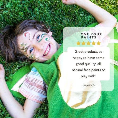 Child with face paint lying on grass, reviewing natural face paints.