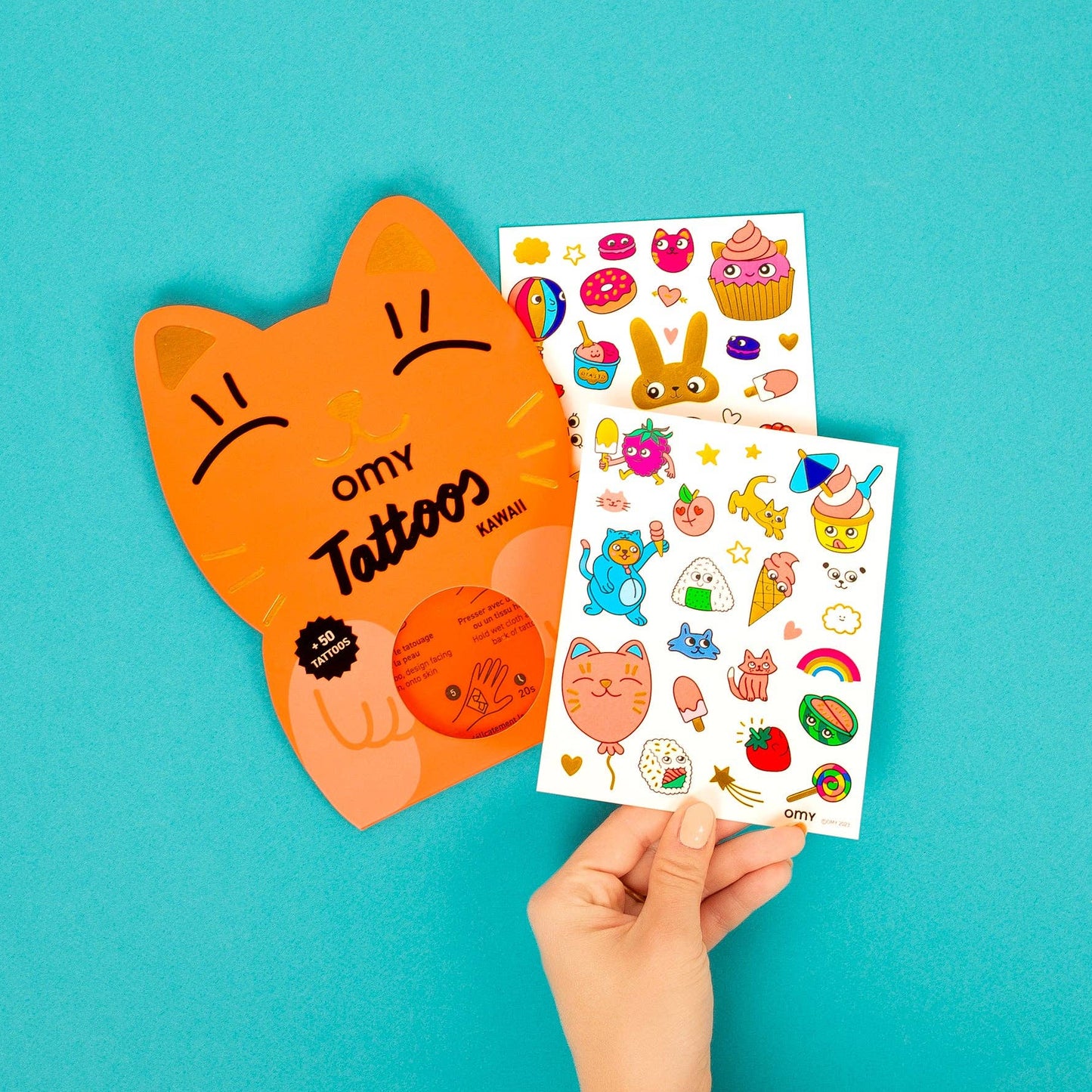 Hand holding a sheet of colorful tattoos with a blue background