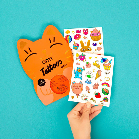 Hand holding a sheet of colorful tattoos with a blue background