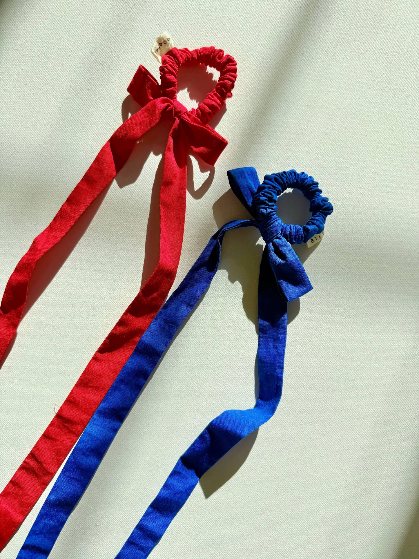 Red and blue hair ties with bows on a light background